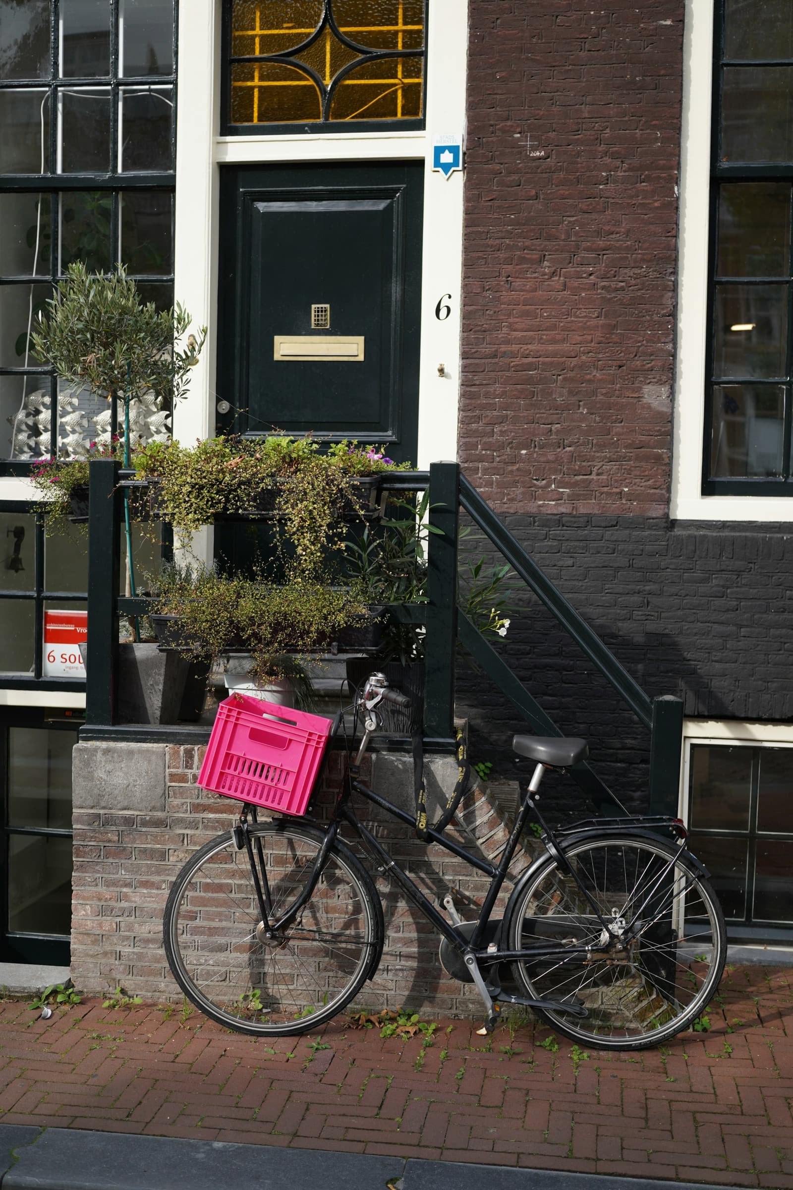 Een fiets met een krat staat voor de voordeur van een bakstenen huis.